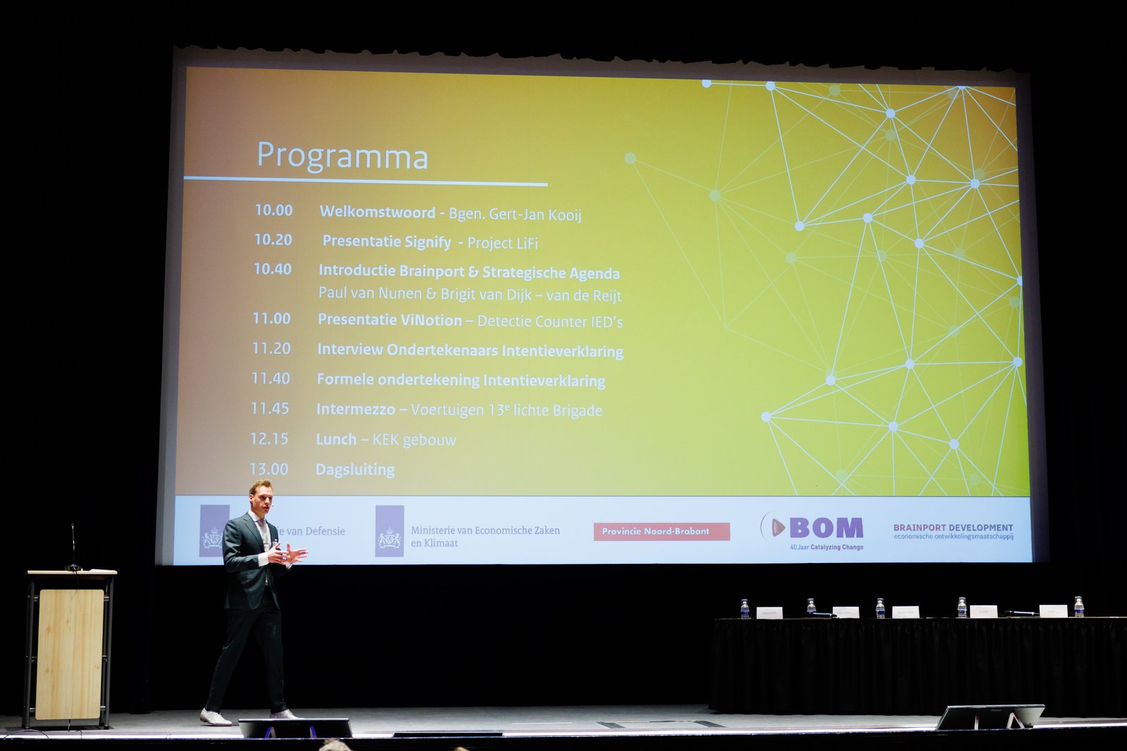 Leander van Bijsterveld als dagvoorzitter bij de Brainport Defensie Innovatieversnelling, op het podium voor het programma
